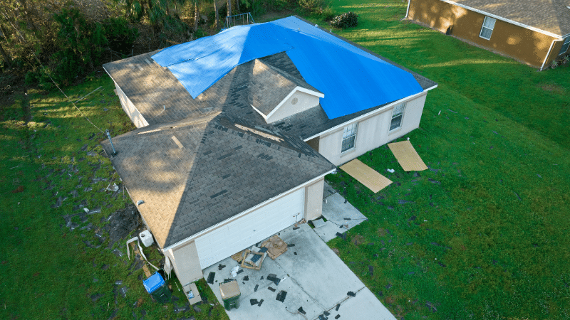 http://Top%20view%20of%20leaking%20house%20roof%20covered%20with%20protective%20tarp%20sheets%20against%20rain%20water%20leaks%20until%20replacement%20of%20asphalt%20shingles.%20Damage%20of%20building%20rooftop%20as%20aftermath%20of%20hurricane%20Ian%20in%20Florida
